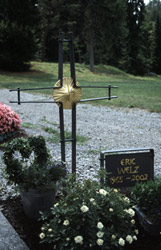 Kreuz mit goldenem Kreis, daneben Namensschild mit goldener Schrift