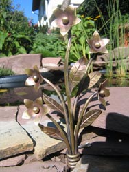 Blumen aus Metall vor einem kleinen Teich